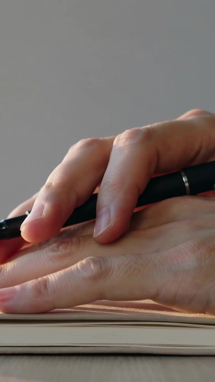 Video verticale: regolando la presa, mani che provano una penna nera su un taccuino sulla scrivania, trascinandola sulla mano