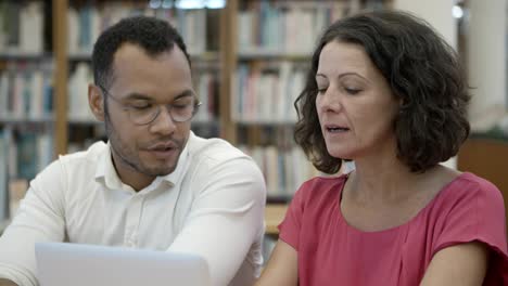 dos personas sentadas en la biblioteca y hablando