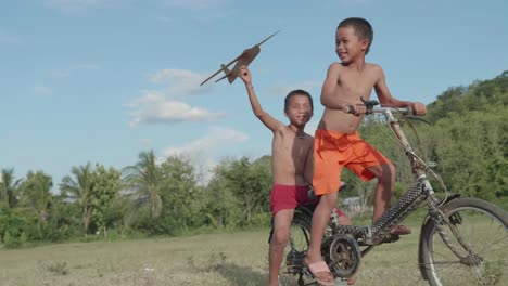 two boys playing with a toy airplane and bicycle