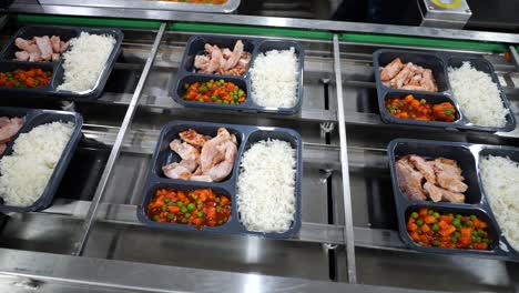 Prepared-meals-on-automatic-conveyor-belt,-packaging-pre-made-lunches