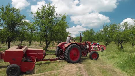 Antenne-Eines-Landwirts,-Der-Sich-Darauf-Vorbereitet,-Mit-Einer-Heuballenpresse-Auf-Einem-Feld-Zu-Arbeiten