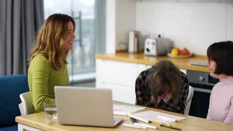 la maestra enseña a las niñas con síndrome de down usando una computadora portátil, divirtiéndose juntas.
