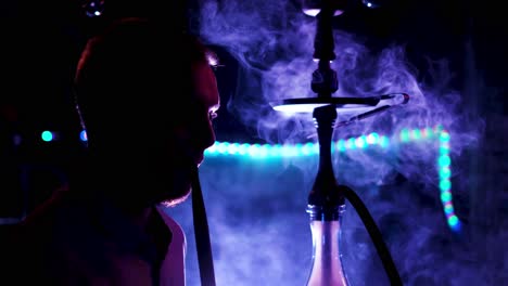 man smoking hookah in a night club