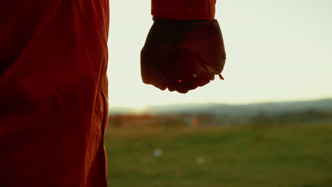 hand of an astronaut with glove shakes a fist in front of a wasteland at sunset