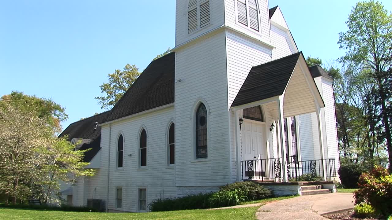오래된 시골 교회가 그 앞의 시골 길 위에 우뚝 서 있습니다.