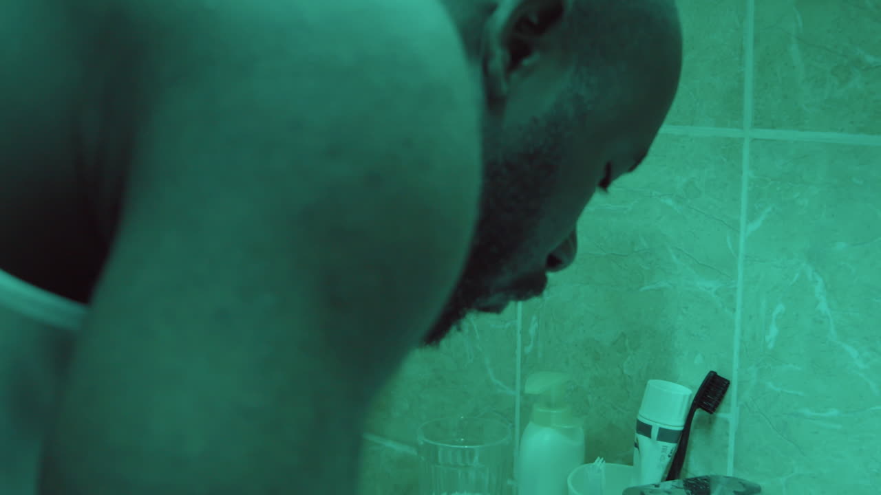 African American Man Washing Face in Bathroom