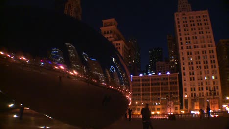 el horizonte del centro de chicago por la noche se refleja parcialmente en el frijol en el parque del milenio 2