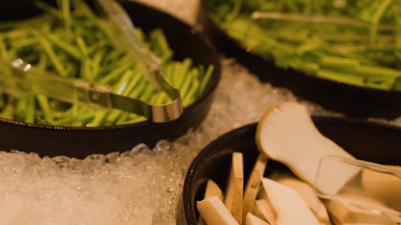 Rotating close-up of fresh vegetables and mushrooms on ice at a hotpot buffet bar