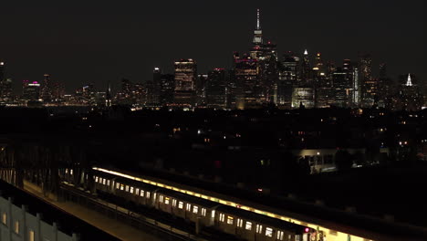 aerial view of new york city at night. a subway train passes in the foreground with the world trade center in the background.