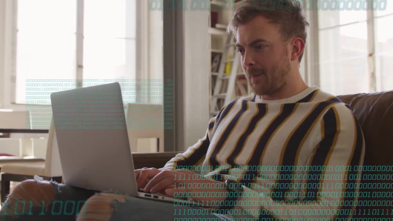 Man typing on laptop on couch, binary digits fading in overlaying torso, visualizing tech data