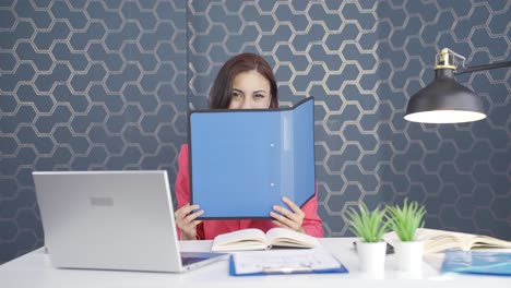 joven mujer de negocios mirando desde detrás de los archivos.