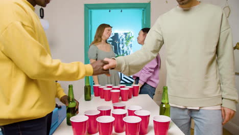 jóvenes amigos multiétnicos jugando pong de cerveza en casa