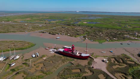 Vista-Aérea-Alrededor-De-Un-Barco-Ligero-Atascado-En-El-Barro-Durante-La-Marea-Baja,-Sunny-Tollesbury,-Reino-Unido---órbita,-Disparo-De-Drones