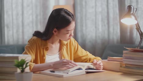young asian female reading books while studying at home