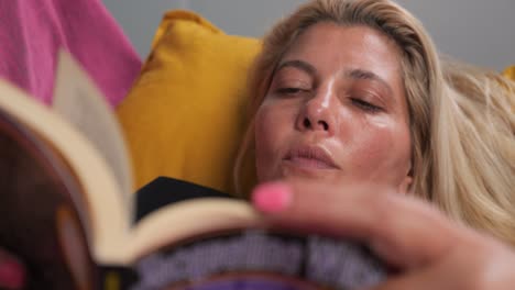 Una-Mujer-Perdida-En-Un-Libro-Mientras-Se-Relaja-En-Casa,-Leyendo