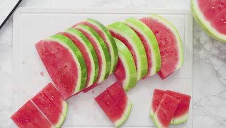 slicing red watermelon into small pieces