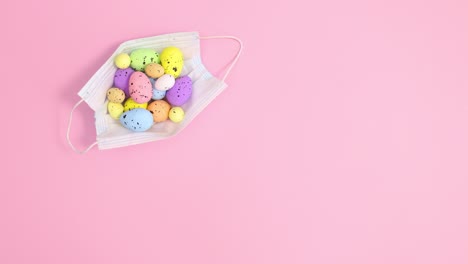 máscara facial móvil con huevos de pascua en fondo rosa pastel. detener el movimiento de colocación plana