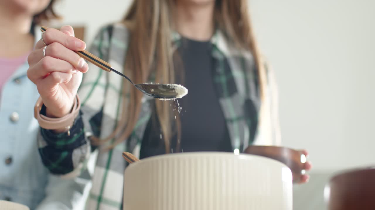 Wooden bowl is tilting as teaspoon is tapping and sifting powder into ribbed bowl for baking