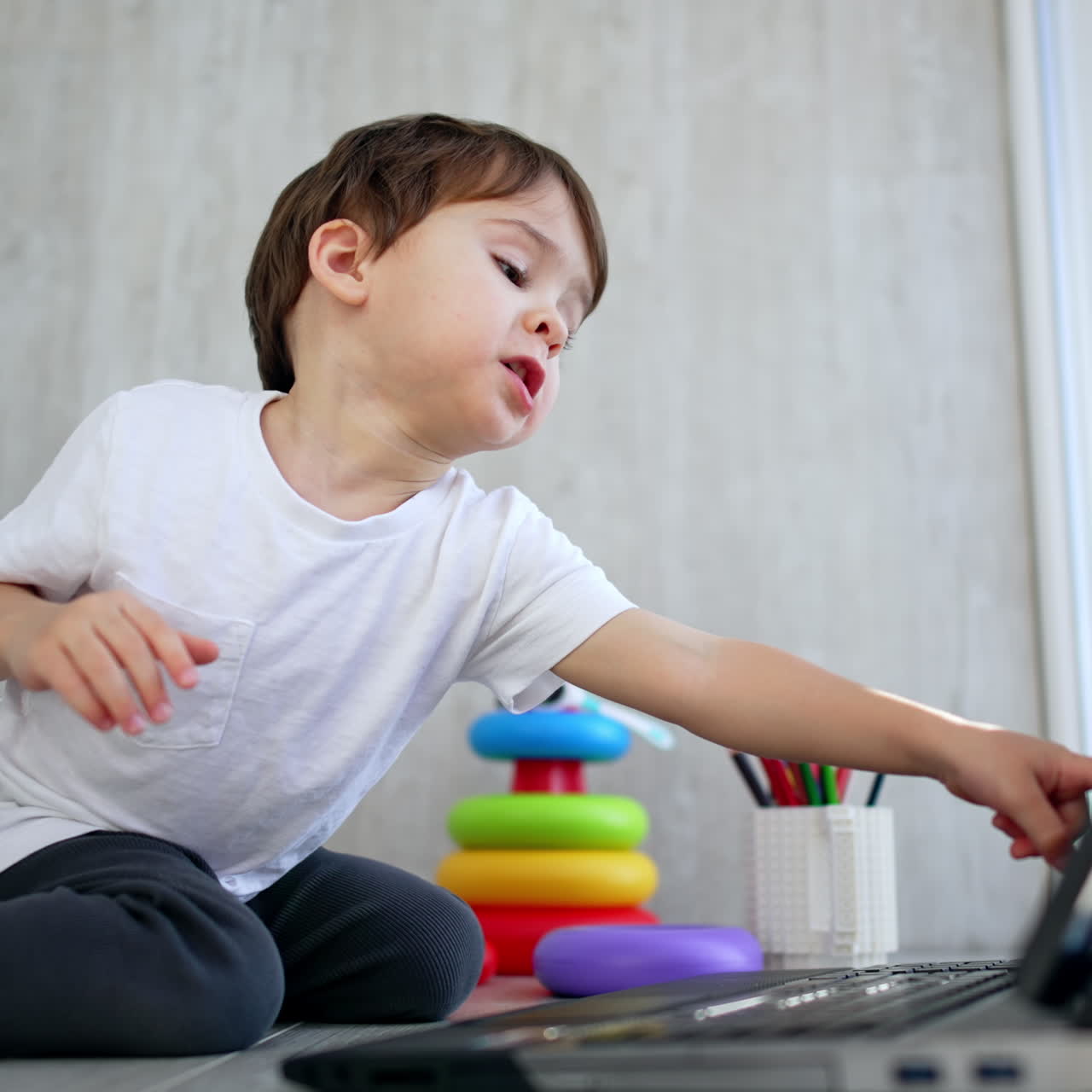 Young Boy Watching and Pointing at Laptop Screen