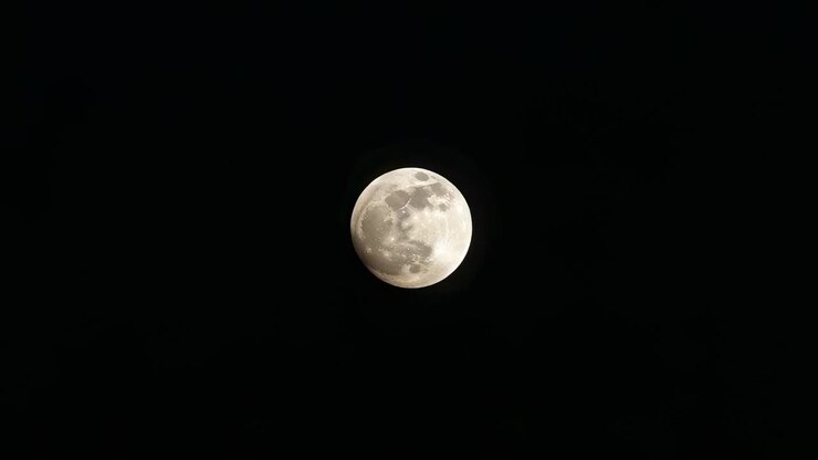 Lua cheia passando por um eclipse parcial no céu ao amanhecer, com a sombra da Terra se aproximando