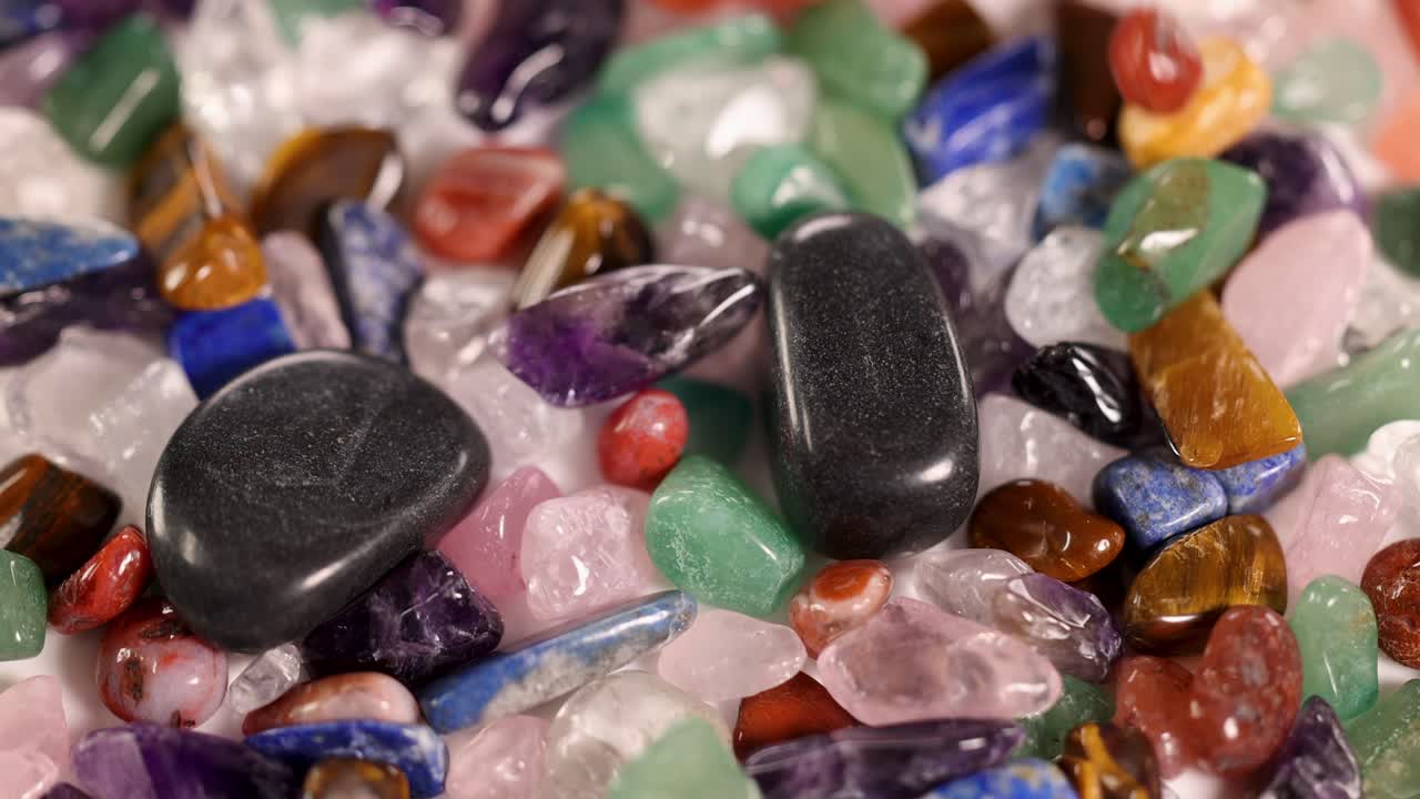 Vibrant chakra stones tumble gracefully, showcasing diverse colors and textures against a soft background, captured in smooth slow motion