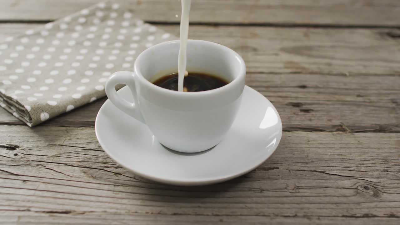 video de una taza blanca de café con leche y una toalla de té sobre un fondo de madera