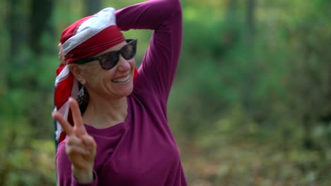 Closeup-of-pretty,-blonde-woman-wrapping-an-American-flag-around-her-head-and-giving-the-camera-the-peace-or-victory-sign