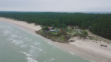 aerial establishing view of baltic sea coast on a overcast winter day, distant house at the beach with white sand, coastal erosion, climate changes, wide orbiting drone shot