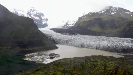 glaciar en islandia con agua y montañas con video de drones moviéndose hacia arriba