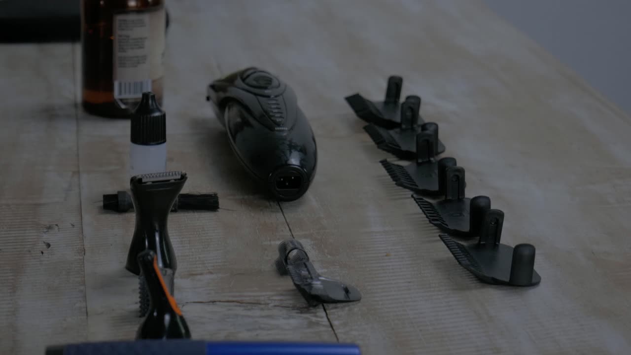 Different men's grooming devices like razor, spacer and beard oil on a wooden table