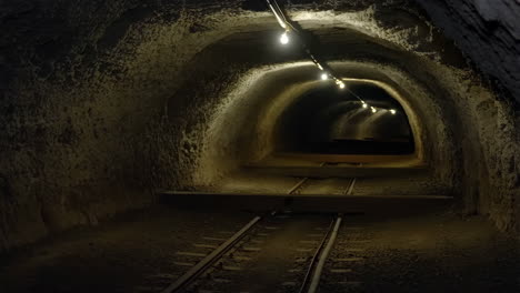 dark underground tunnel with railway tracks and lights