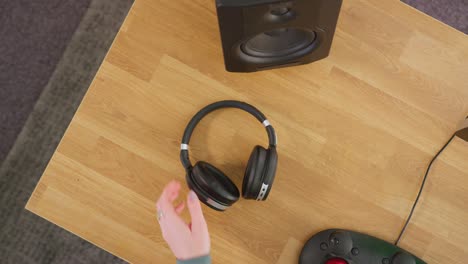 close up overhead view of female video editor taking off wireless headphones and working at computer with green screen in creative office - shot in slow motion