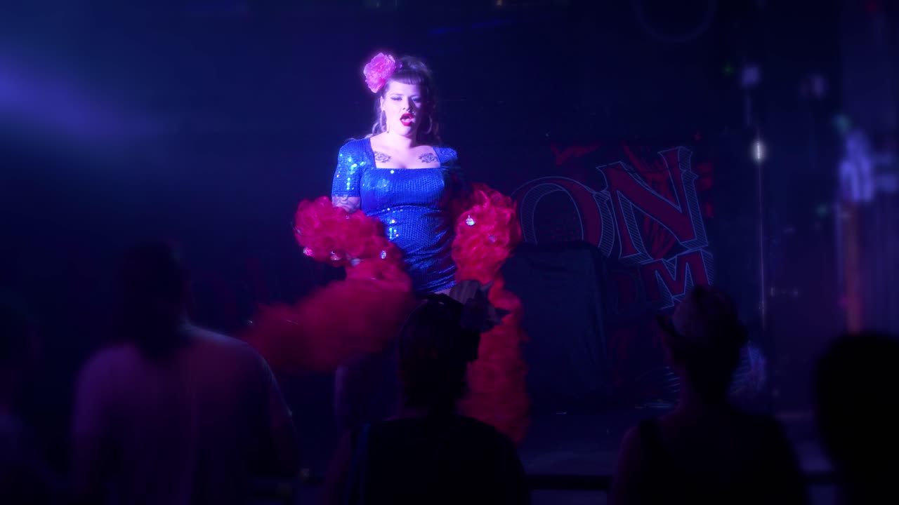 bailarina burlesca con curvas en el escenario con una boa de plumas rojas durante una actuación sexy en vivo