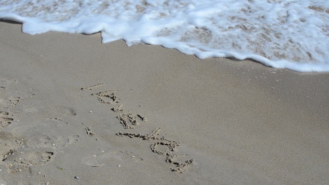 Inscripción 'Te amo'. La inscripción es borrada por una ola.