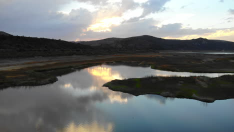 Aerial-drone-fly-in-over-island-and-dried-up-Irvine-Lake-in-Southern-California-at-beautiful-sunset--lake-is-almost-empty-due-to-drought