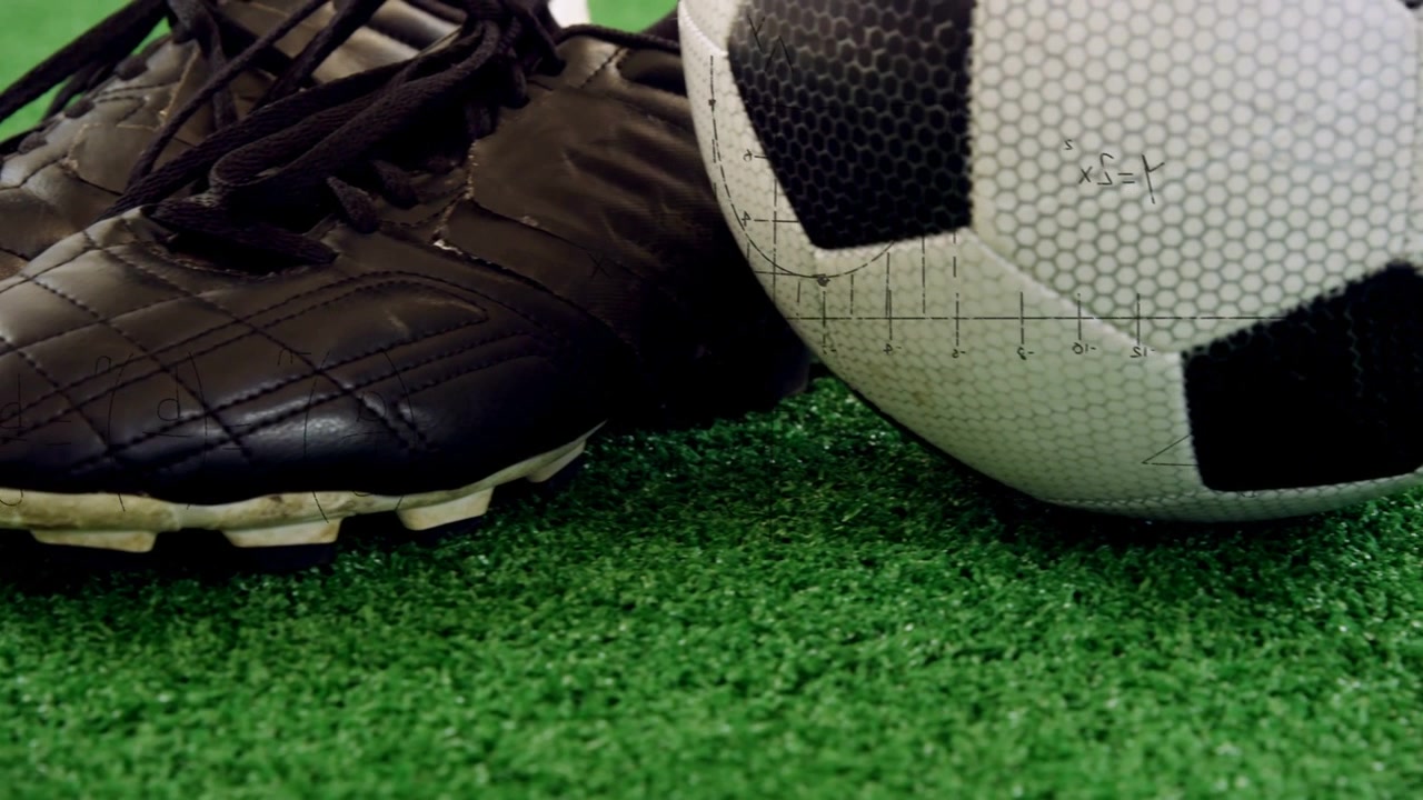 Chuteiras de futebol pretas em gramado sintético se deslocando para a esquerda enquanto a câmera faz um movimento panorâmico e a bola se move para o centro, exibindo esportes.
