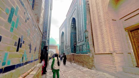 people walking through an ancient alleyway with ornate tiled buildings in samarkand