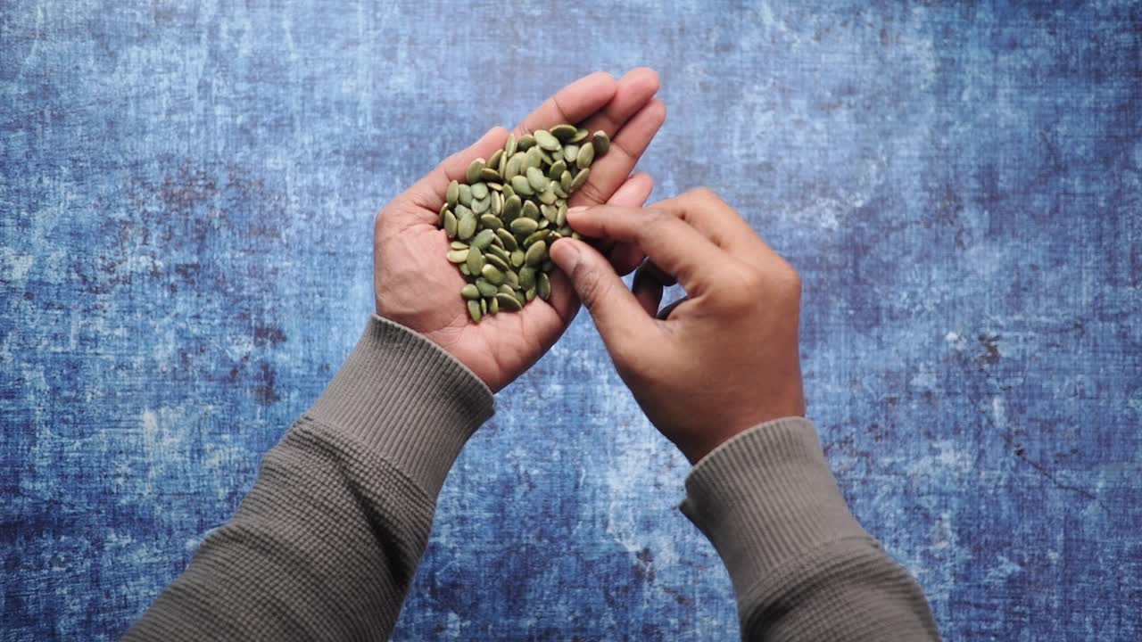 Groene pompoenpitten met de hand uit een hoop selecteren