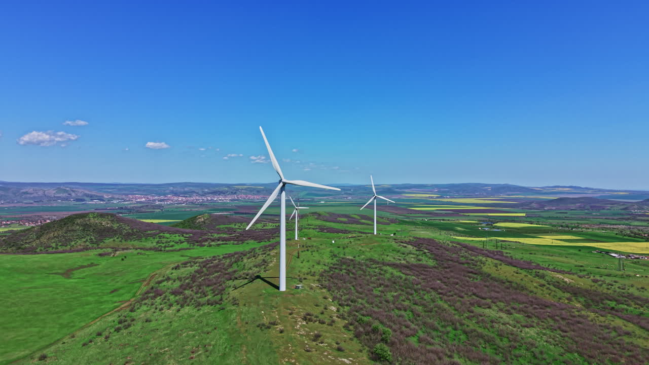 Wind turbines generate renewable energy on a sunny day in a green landscape near a small town in the countryside