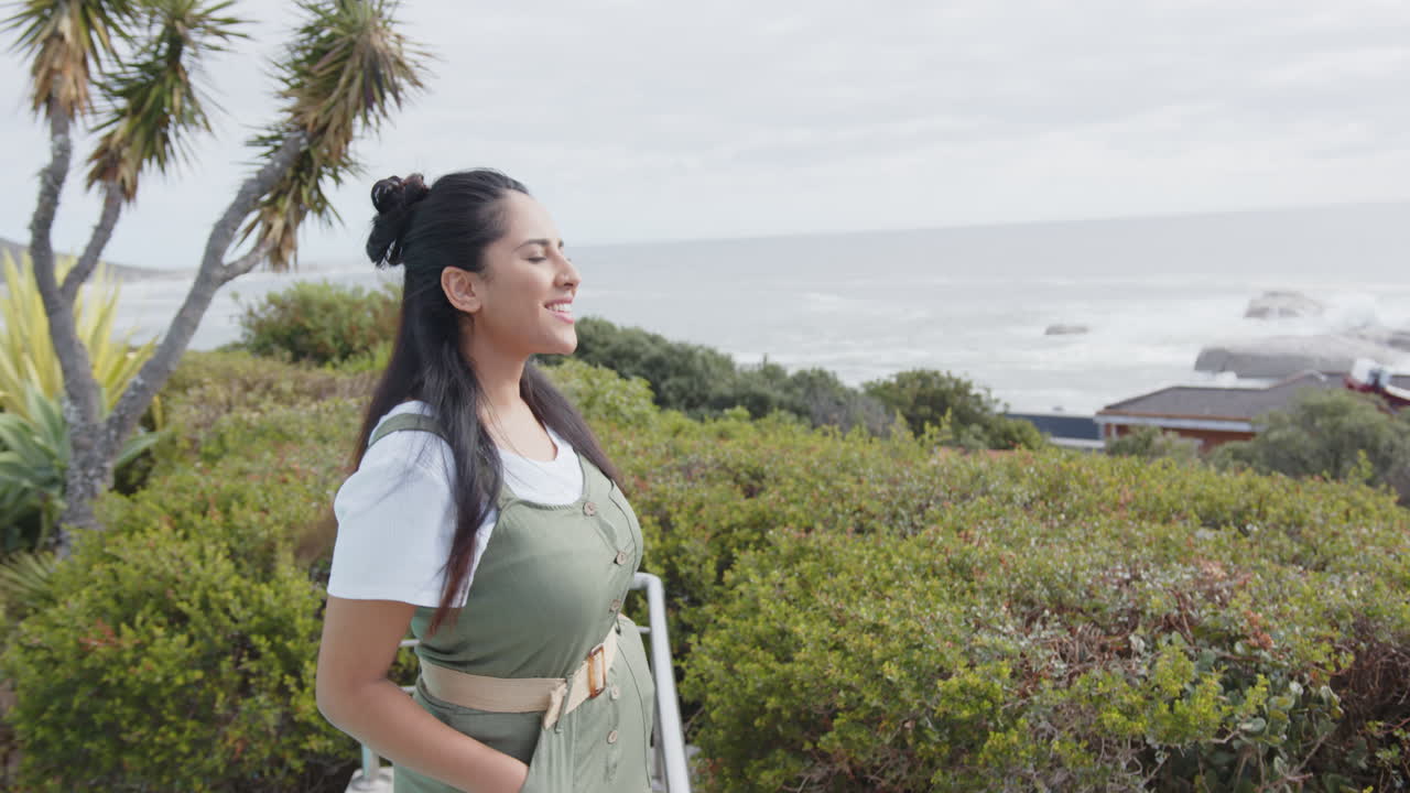 Enjoying nature, asian woman standing with ocean view, feeling relaxed, on balcony, copy space