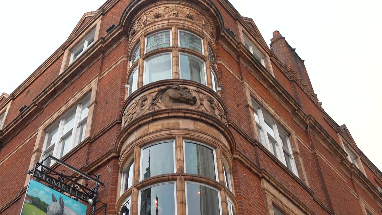 Edificio angolare in mattoni rossi a Londra visto dal basso, che mostra finestre curve e dettagli decorativi della facciata. Vista diurna di architettura residenziale contro il cielo