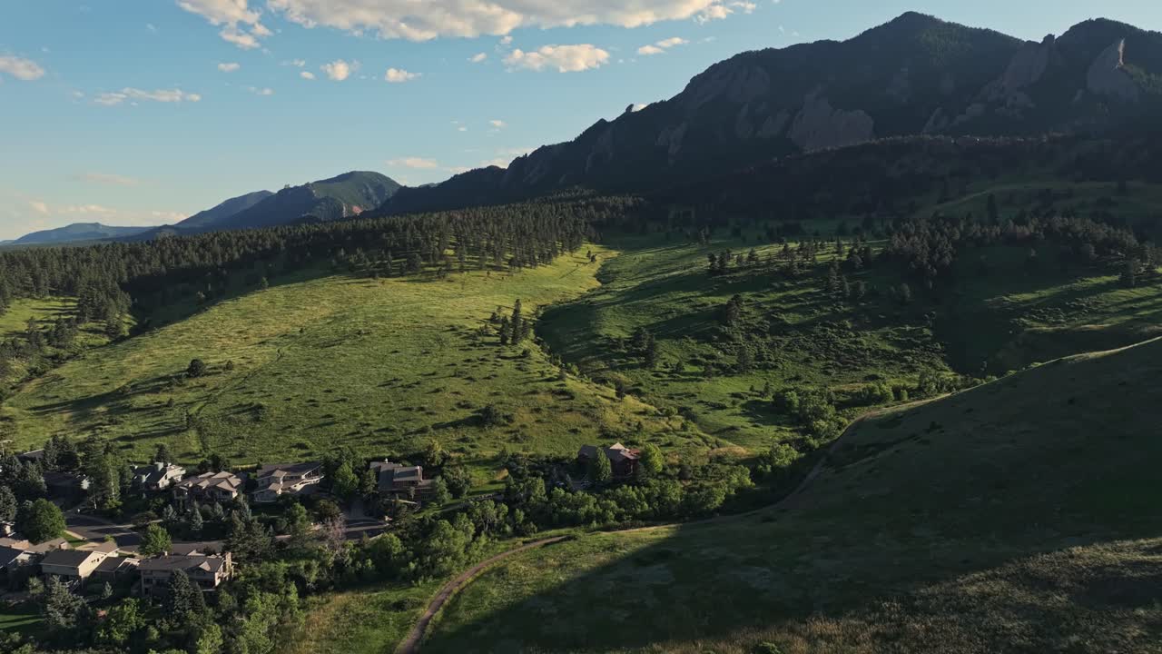 aerial sobre las colinas boscosas de boulder con los picos de las montañas flatirons en el fondo, colorado, ee.uu.