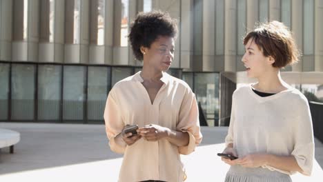 front view of relaxed women talking while walking on street