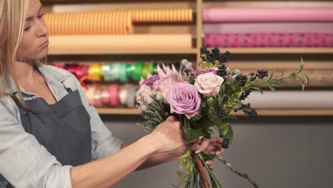 vista lateral de una artista floral profesional arreglando un hermoso ramo en el tiro de flores. ella está combinando diferentes flores