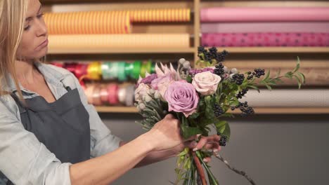 side view of professional female floral artist arranging beautiful bouquet at flower shot. she is combining different flowers