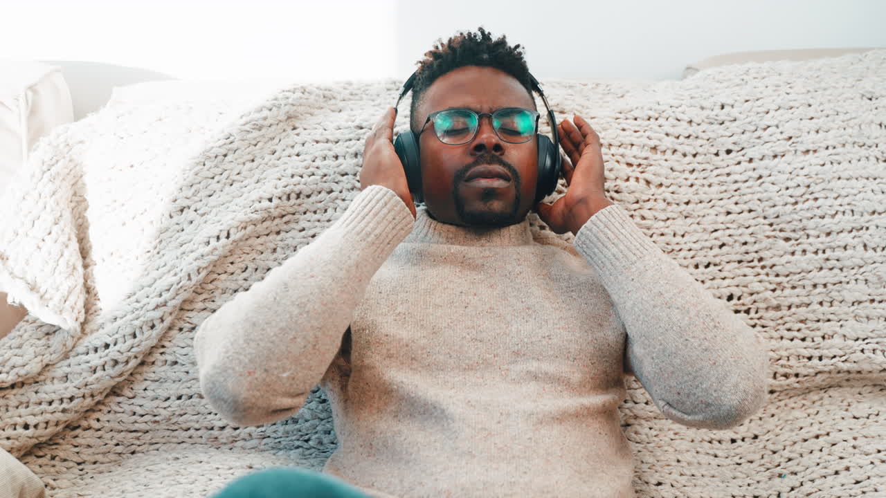 Mann som slapper av på en sofa med hodetelefoner