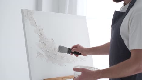 an artist paints a piece of art on a canvas with color oil painting at home an artist works and - an artist paints a piece of art on a canvas with color oil painting at home. an artist works and creatively works on an abstract oil painting in the workshop. hobby concept