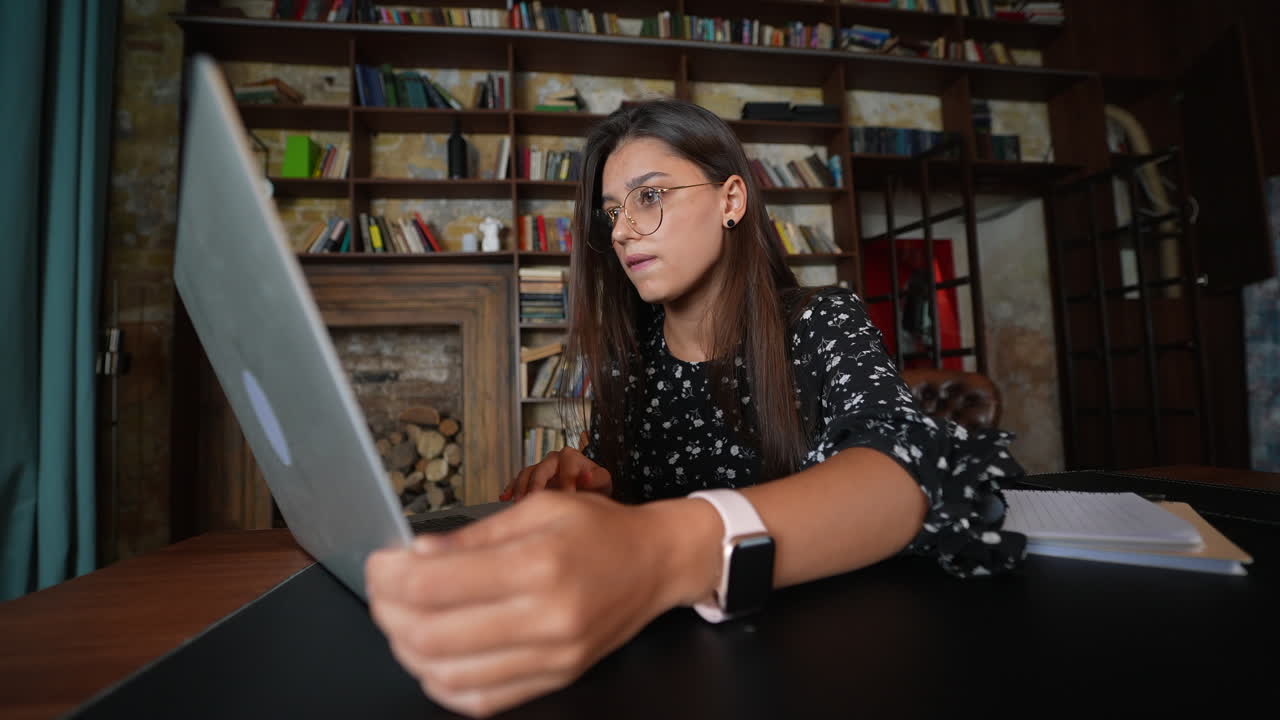 mujer trabajando en una computadora portátil en una biblioteca