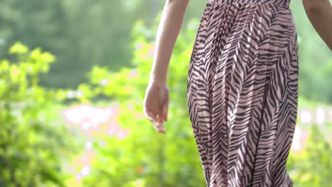 Young-woman-in-patterned-skirt-walking-in-the-forest-and-spinning-around