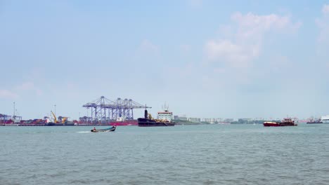 Panoramic-view-of-the-Kochi-harbour-area,-in-Ernakulam,-Kerala-India-with-speed-boats-passing-and-ships-cruising-in-the-waters